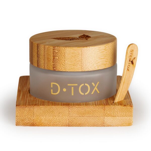 A jar of D.TOX sits on a bamboo stand. It has a bamboo lid and a bamboo applicator